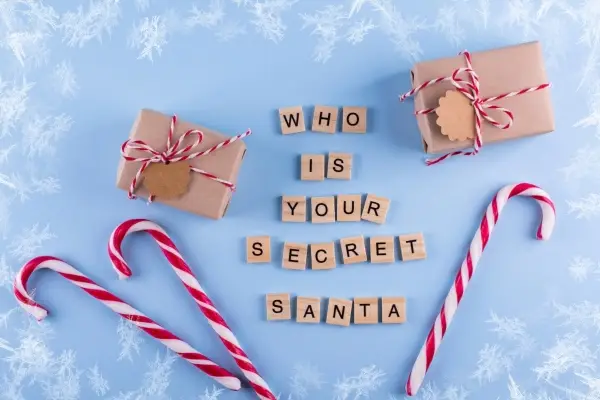 Wooden letters spelling "Who is your secret Santa" with candy canes and two gifts.