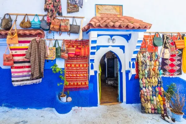 Blue and white tiled archway entrance to a traditional Moroccan store with colorful souvenirs.