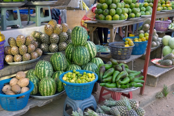 Market stall piled high with green vegetables and fruits in Ghana as traditional Christmas gifts.