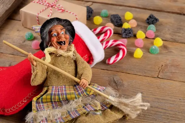 Doll representing the Italian Christmas witch, La Befana, with a broom and various candies.