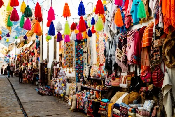 Outdoor Peruvian market stall with rows of hanging, colorful cloth umbrellas or flags.