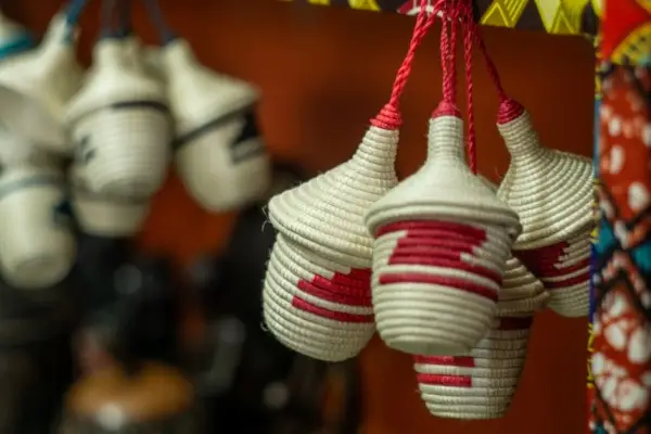 Two woven, decorative bags with red and white rope, hanging up from Rwanda.