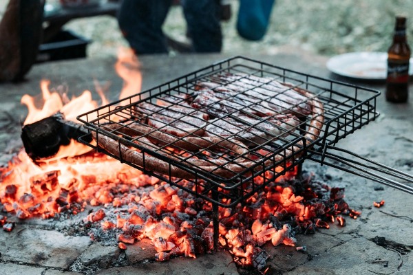 Meat cooking on an open grill over glowing coals for South African Christmas Braai.
