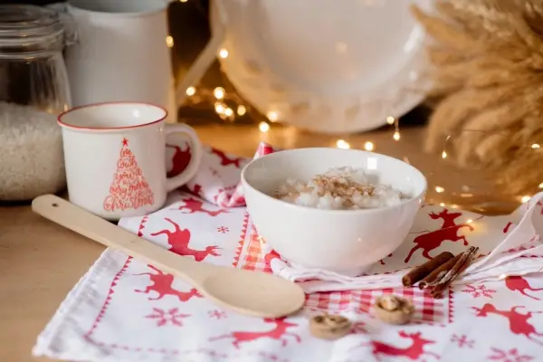 A warm and comforting bowl of porridge topped with nuts, a perfect example of a simple hygge breakfast, with festive lights in the background.