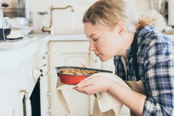 A woman placing a freshly prepared dish, like a fruit crumble, into the oven, embodying the hygge tradition of homemade baking.