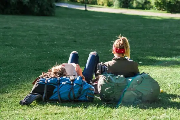 Two people relaxing together on the grass in a sunny park, embodying the hygge concept of enjoying simple, peaceful moments outdoors.