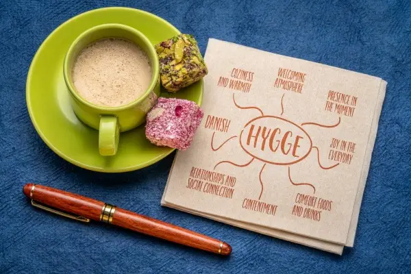 A cozy hygge scene featuring a warm drink and a wooden board with a mind map explaining the Danish concept of 'Hygge,' making it a thoughtful gift.