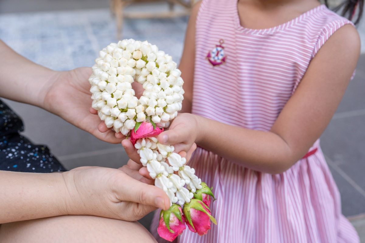 Thai mother's day: a daughter holding a traditional Thai jasmine flower garland offering it to her mother.
