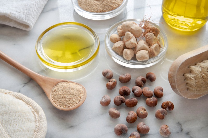 African natural cosmetic ingredients featuring baobab fruit, seed, and oil on a marble background.