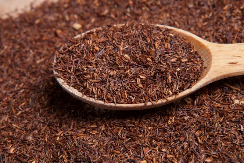 Loose leaf rooibos tea displayed in a round wooden spoon.