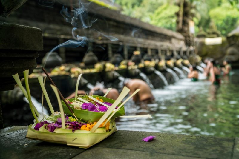 The holy spring water of Pura Tirta Empul temple in Bali, Indonesia. People participating in a traditional Balinese water purification ritual at a stone temple.