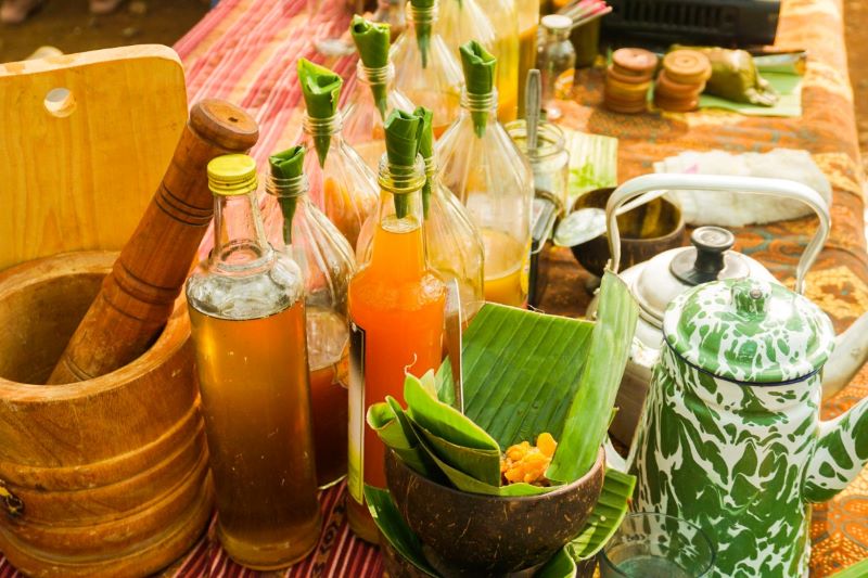 Traditional Indonesian Jamu herbal wellness drinks in glass bottles with fresh ingredients.