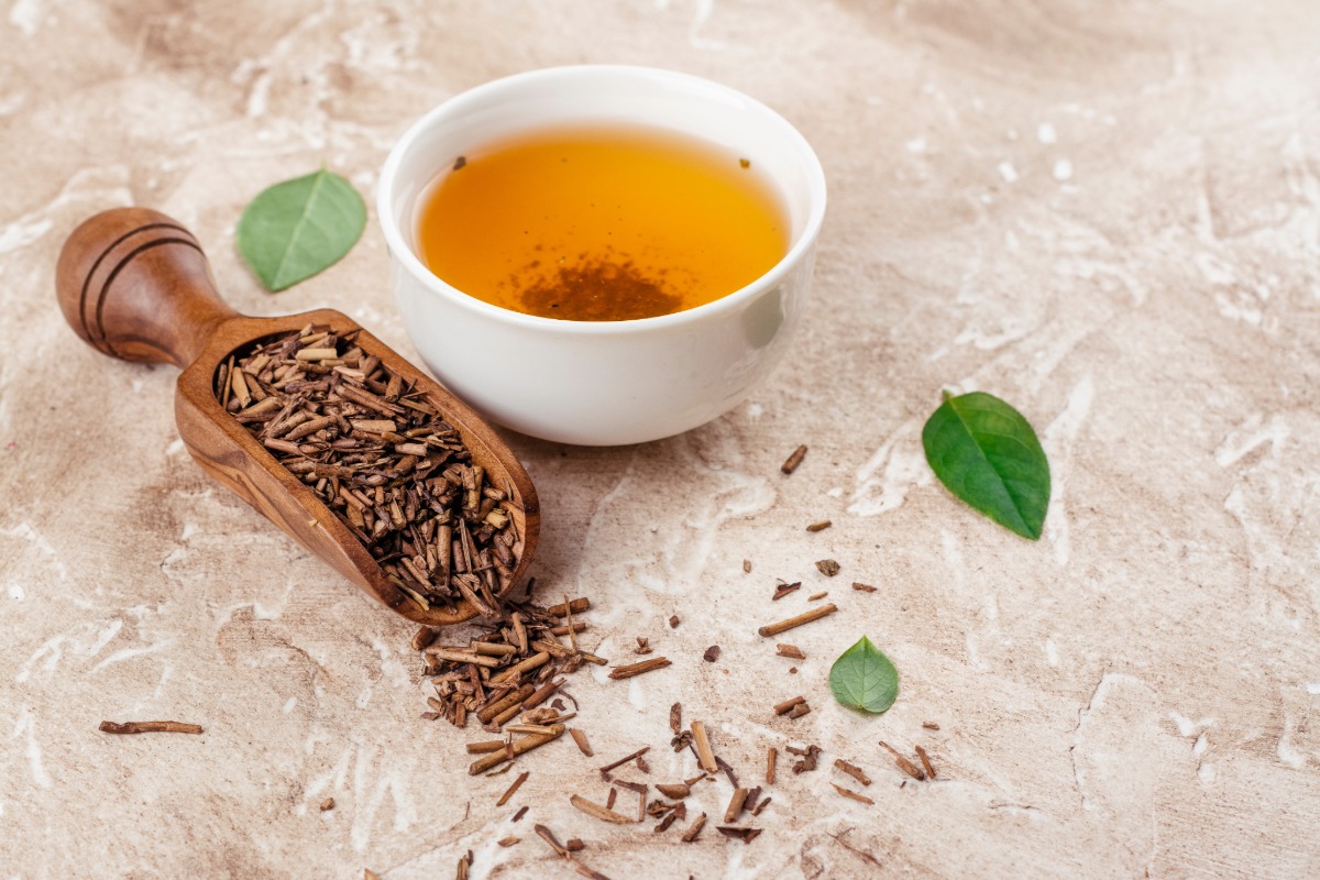 Dry hojicha green tea leaves and hojicha tea on a stone table.