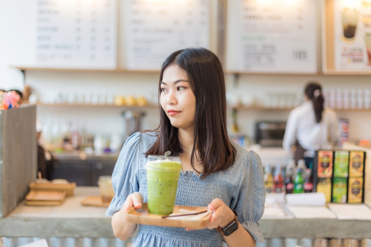 Japanese matcha store. Asian smiling women with ice matcha green tea in art cafe.